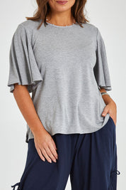 Model Monique wearing size 14 of the Flutter By Tee in colour Lightgrey (Grey), from the front, cropped image