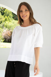 A model wearing the Bliss Top in colour White (White), from the front, cropped image