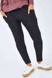Model Summer wearing size 10 of the Fundamental Weekend Pant in colour Black (Black), from the front, cropped image