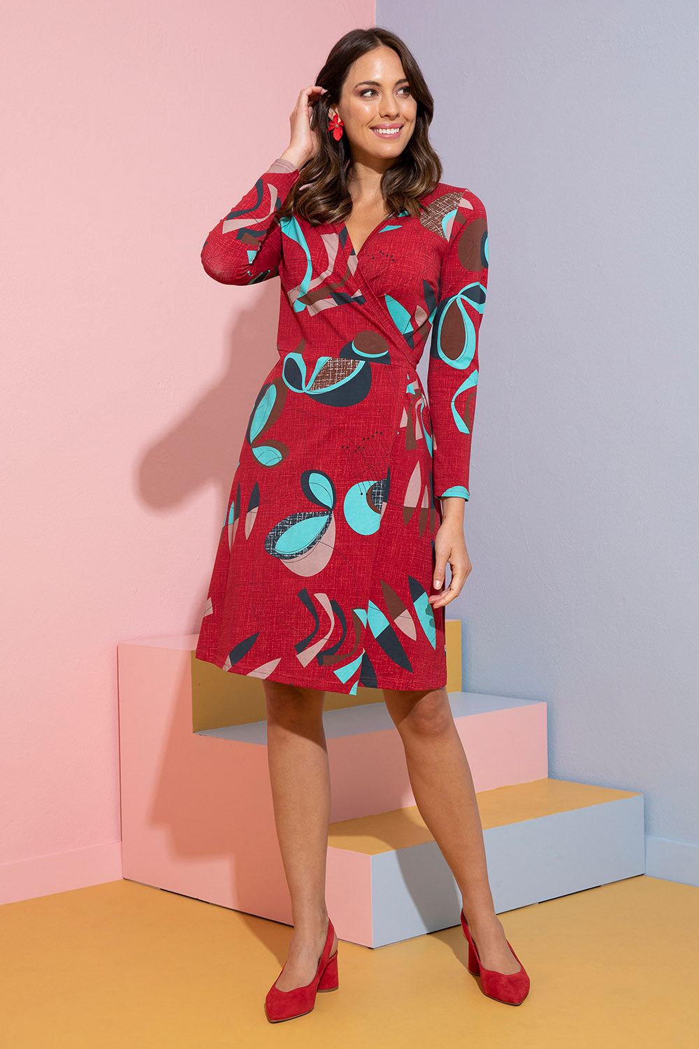 Model Madeline wearing size S of the Fifty Wrap Dress in colour Fiftyred (Red), from the front, showing the whole outfit