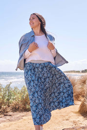 A model wearing the Tilli Pleated Skirt in colour Indiflower (Blue), from the front, showing the whole outfit