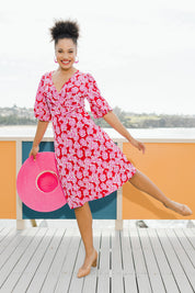 Model Olivia wearing size 10 of the Gathered Waist Faux Wrap Dress in colour Roses (Red), from the front, showing the whole outfit