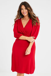 Model Laura wearing size 14 of the Gathered Waist Faux Wrap Dress in colour Flame (Red), from the front, cropped image