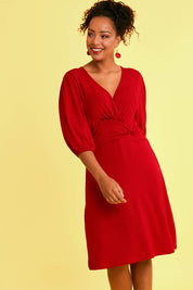 Model Noli wearing size 14 of the Gathered Waist Faux Wrap Dress in colour Flame (Red), from the front, showing the whole outfit