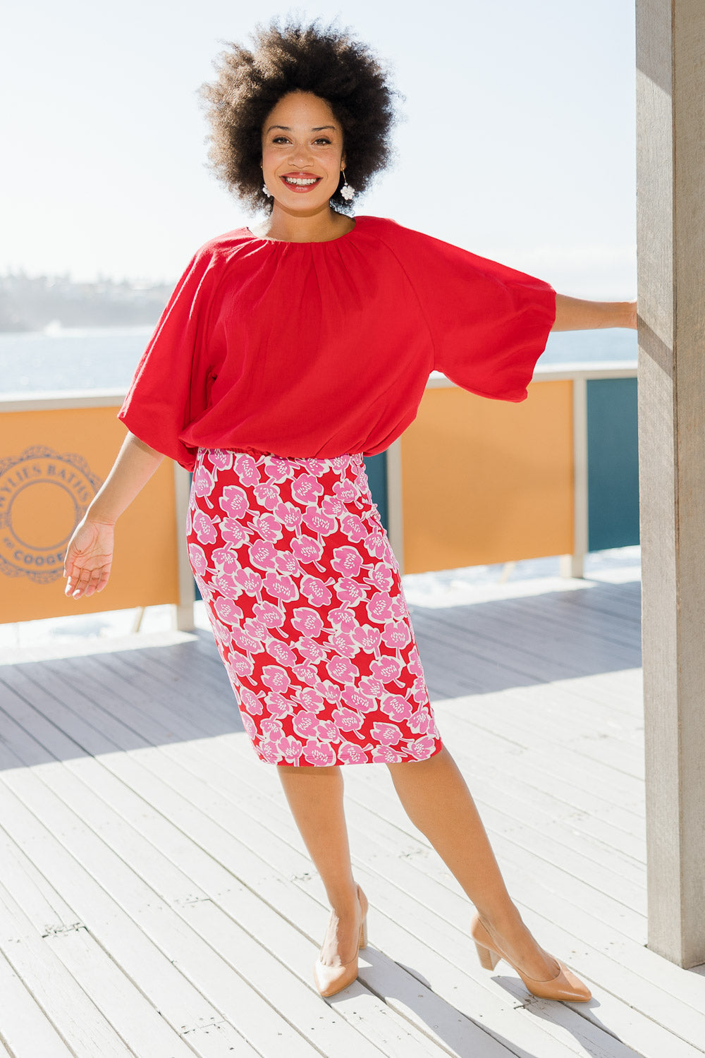 Model Olivia wearing size 10 of the Printed Tube Skirt in colour Roses (Red), from the front, showing the whole outfit