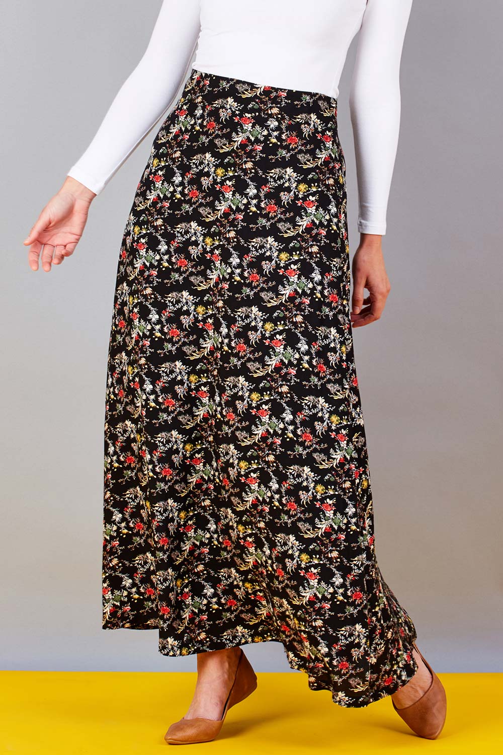 Model Riina wearing size 10 of the Printed Maxi Skirt in colour BlackFluer (Black), from the front, cropped image