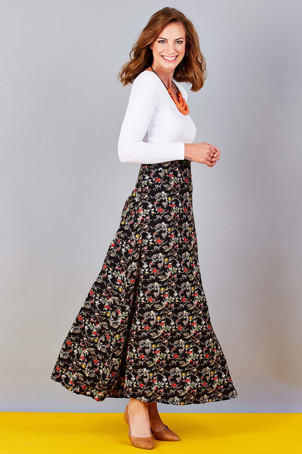 Model Riina wearing size 10 of the Printed Maxi Skirt in colour BlackFluer (Black), from the front, showing the whole outfit