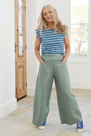 A model wearing the Ollie Pant in colour Eucalyptus (Green), from the front, showing the whole outfit