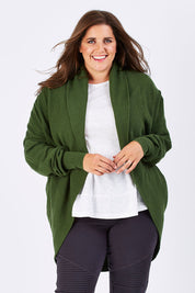 Model Mae wearing size XL of the Natural Cocoon Cardigan in colour Vineyard (Green), from the front, cropped image