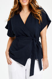 Model Laura wearing size 14 of the Linen Cotton Wrap Blouse in colour Navy (Blue), from the front, cropped image