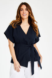 Model Laura wearing size 14 of the Linen Cotton Wrap Blouse in colour Navy (Blue), from the front, cropped image
