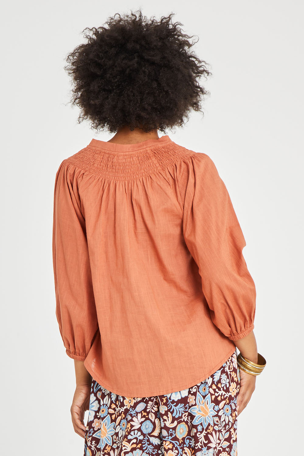 Model Olivia wearing size 10 of the Gaia Top in colour Rust, from the back