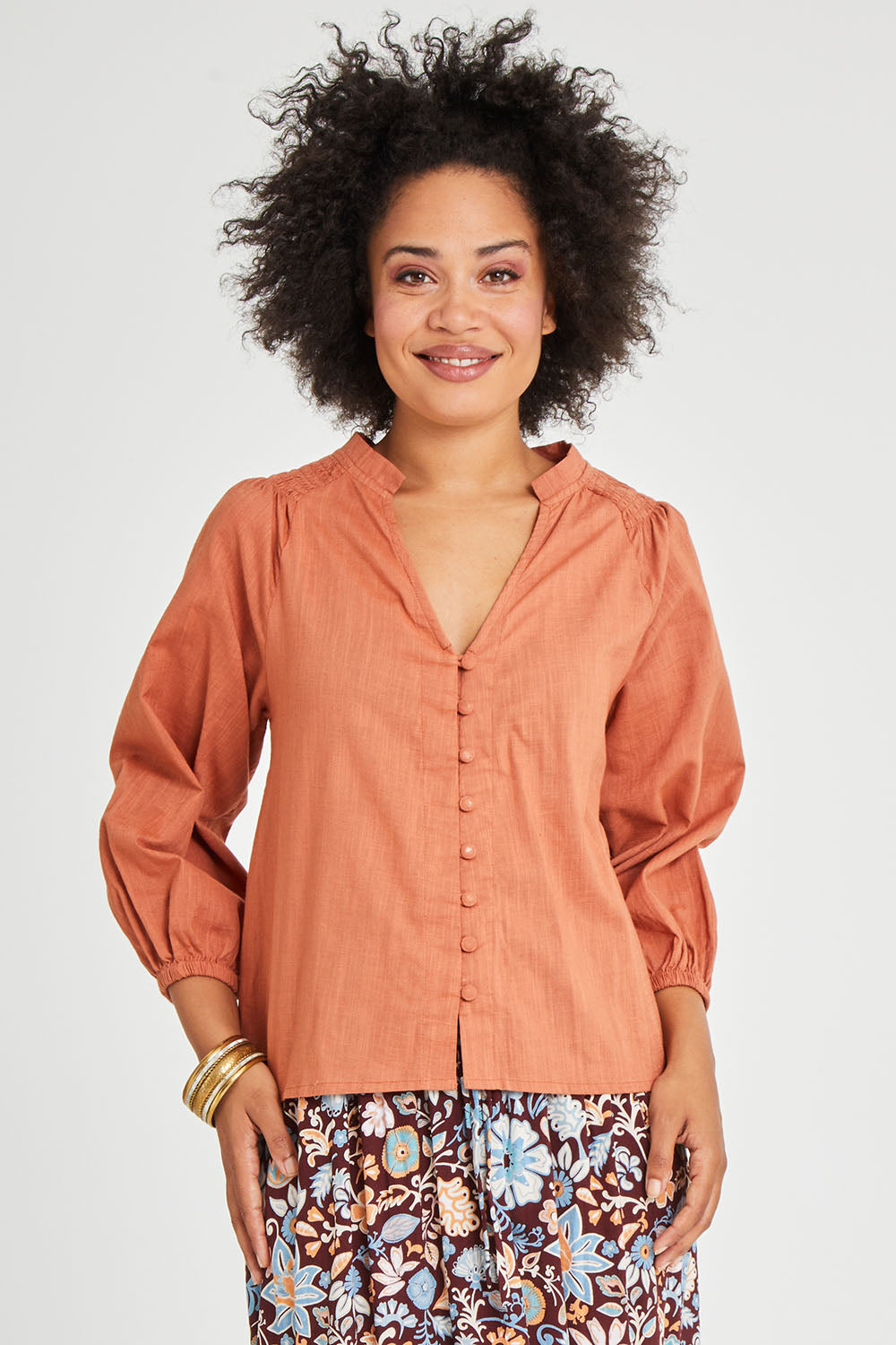 Model Olivia wearing size 10 of the Gaia Top in colour Rust, from the front, cropped image