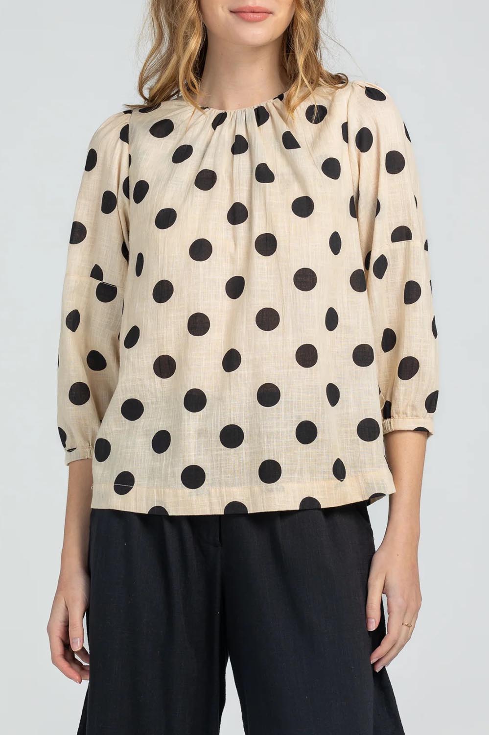 A model wearing the Lara Top in colour Whitespot (White), from the front, cropped image
