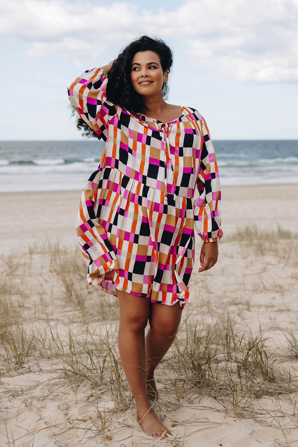 A model wearing the Sunset Gingham Tie Front Midi Dress in colour Gingham (Pink), from the front, showing the whole outfit