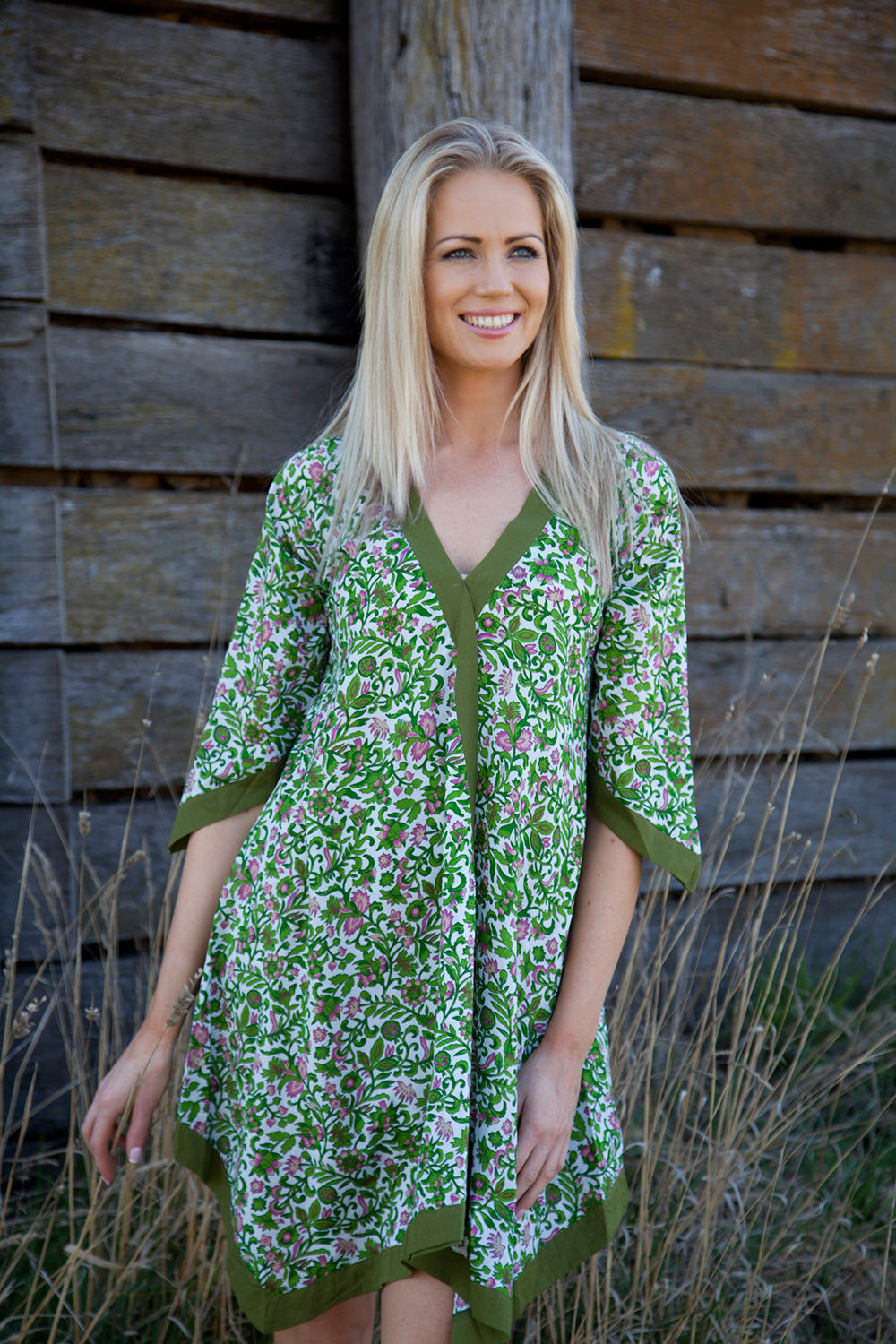 A model wearing the Libby Poncho in colour PinkFlower (Green), from the front, showing the whole outfit