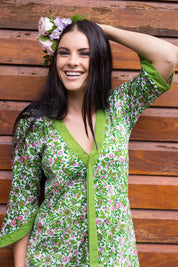 A model wearing the Libby Poncho in colour PinkFlower (Green), from the front, showing the whole outfit