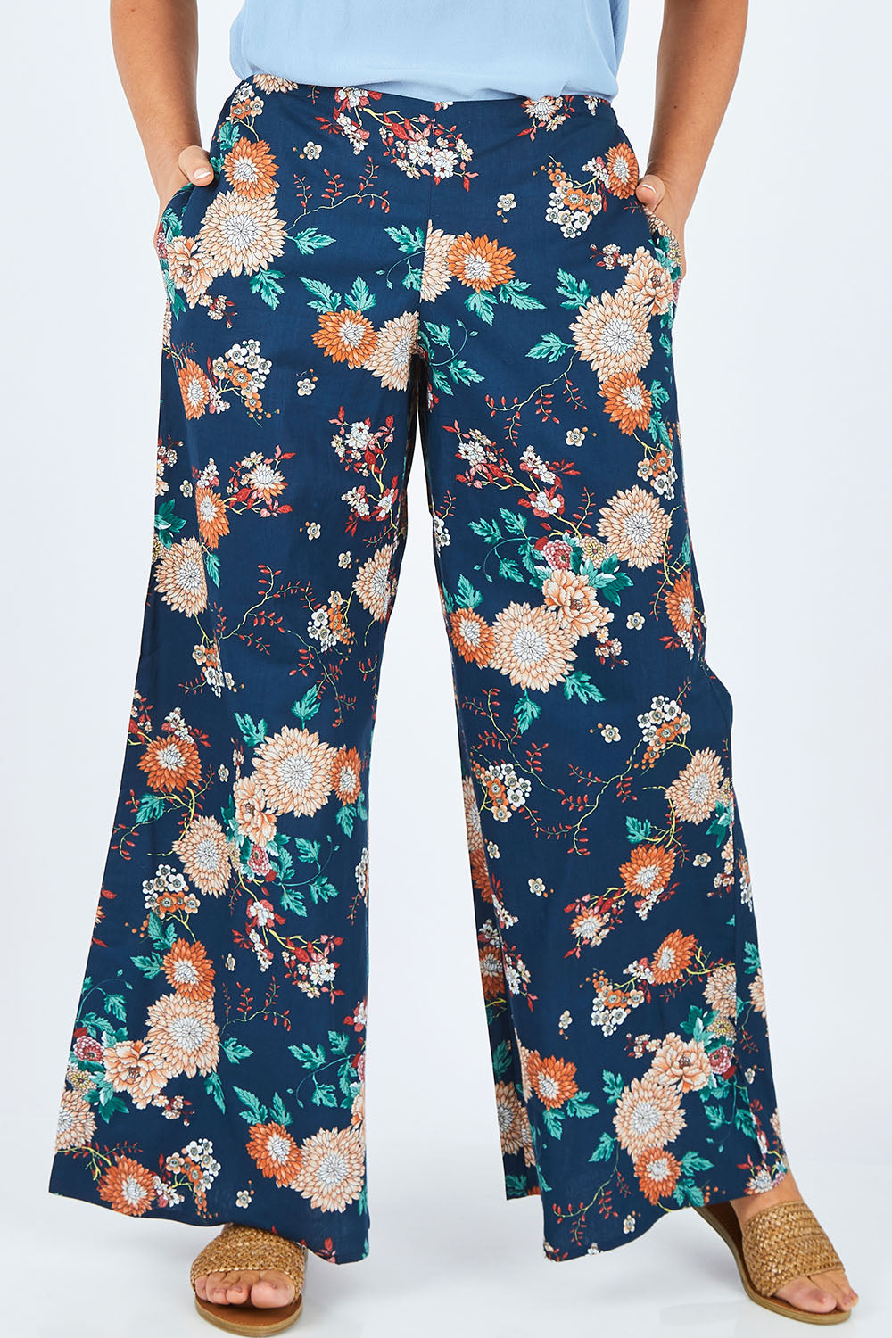 Model Abby wearing size L of the Sarita Pant in colour Maya (Blue), from the front, cropped image