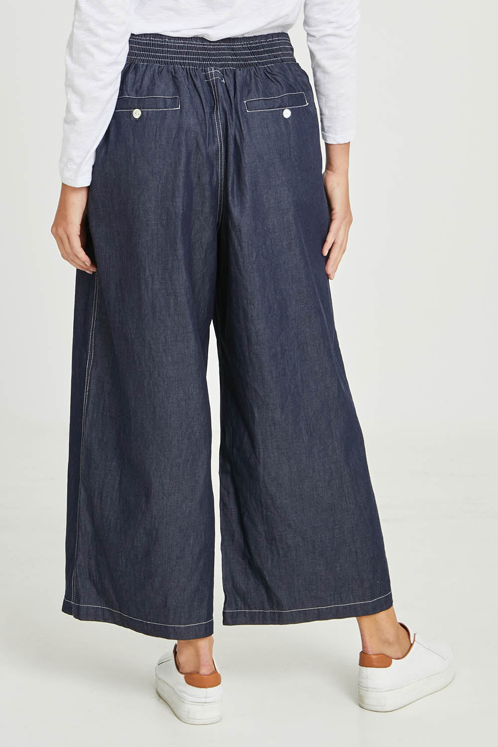Model Madeline wearing size S of the Pula Pant in colour Denim (Blue), from the back