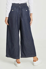 Model Madeline wearing size S of the Pula Pant in colour Denim (Blue), from the back
