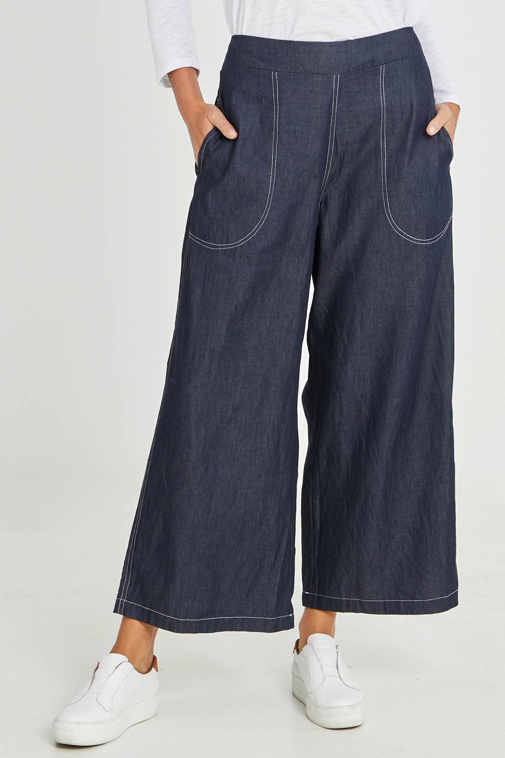 Model Madeline wearing size S of the Pula Pant in colour Denim (Blue), from the front, cropped image