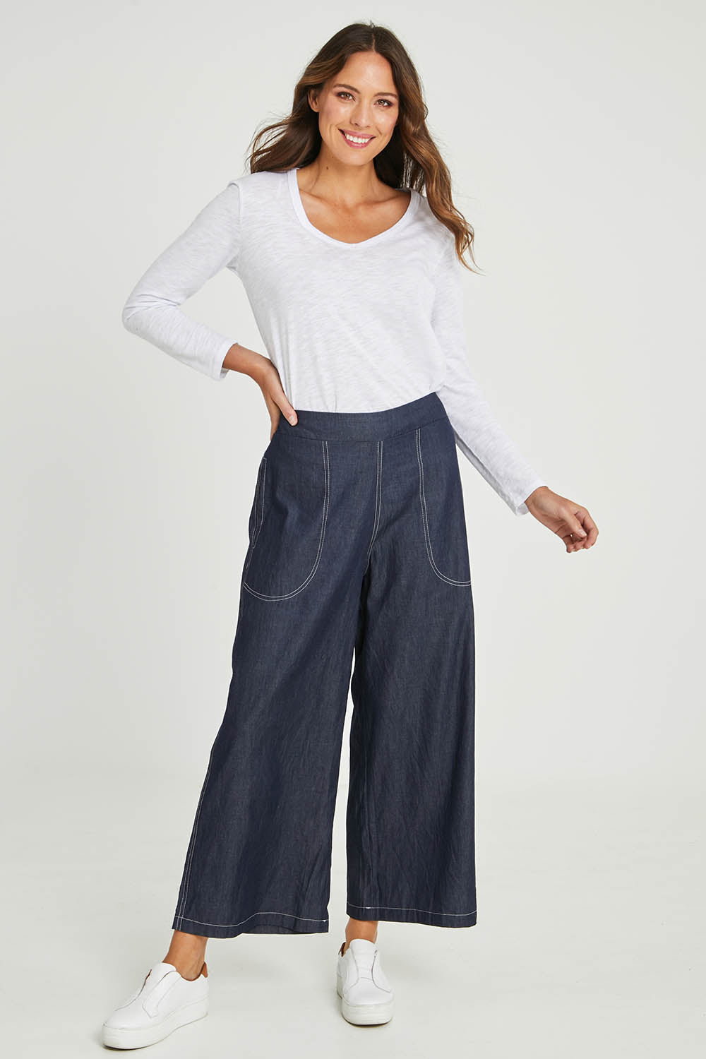 Model Madeline wearing size S of the Pula Pant in colour Denim (Blue), from the front, showing the whole outfit