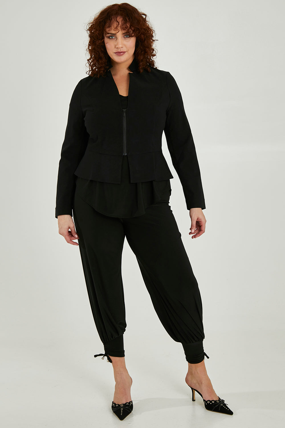 Model Maddy wearing size 16 of the Front Zip Peplum Jacket in colour Black (Black), from the front, showing the whole outfit