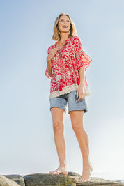 Model Riina wearing size 10 of the Maroubra Beach Cotton Blouse in colour Red (Red), from the front, showing the whole outfit