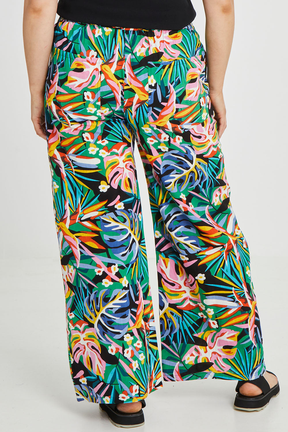 Model Keeara wearing size 16 of the Stella Print Pant in colour Rainforest (Blue), from the back