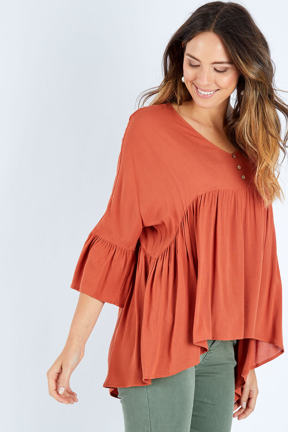 Model Madeline wearing size S of the Ruffle Hem Top in colour Brick (Red), from the front, cropped image