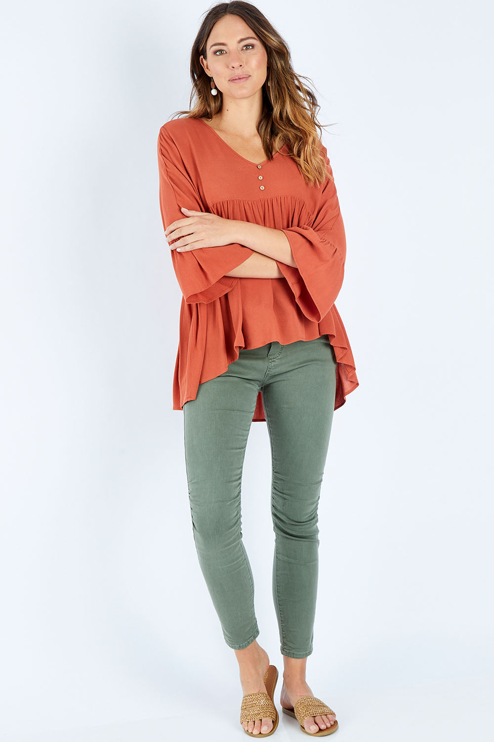 Model Madeline wearing size S of the Ruffle Hem Top in colour Brick (Red), from the front, showing the whole outfit