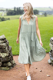 Model Kelly wearing size S of the Gingham Reversible Dress in colour Thyme (Green), from the front, showing the whole outfit