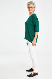 Model Elise wearing size S of the Relaxed High Low Bamboo Top in colour Forest (Green), from the front, showing the whole outfit