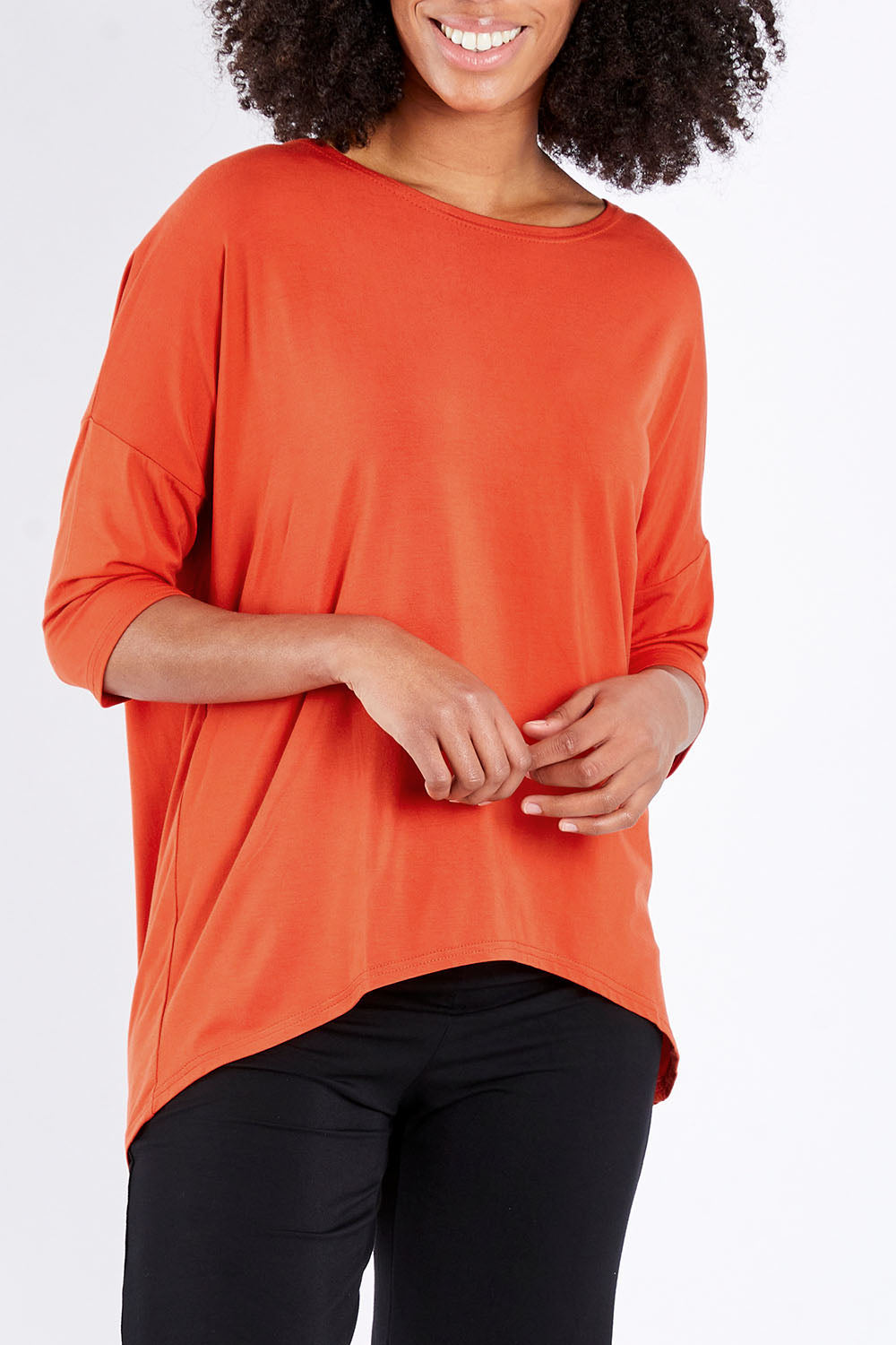 Model Schanez wearing size S of the Relaxed High Low Bamboo Top in colour Tangerine, from the front, cropped image
