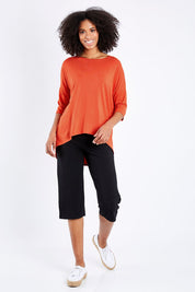 Model Schanez wearing size S of the Relaxed High Low Bamboo Top in colour Tangerine, from the front, showing the whole outfit