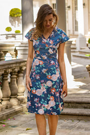 A model wearing the Astrid Dress in colour Maya (Blue), from the front, showing the whole outfit