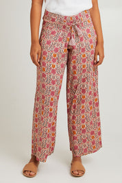 Model Olivia wearing the Nat Pant in colour Rhodes (Pink), from the front, cropped image