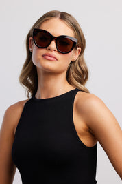 A model wearing The Forever Classic Sunglasses in colour Turtle, from the front, showing the whole outfit