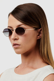A model wearing the Helsinki Sunglasses in colour Goldgreen (Metallics), from the front, cropped image