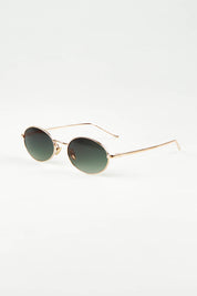 A model wearing the Helsinki Sunglasses in colour Goldgreen (Metallics), from the front, showing the whole outfit