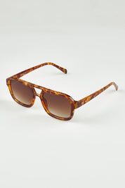 A model wearing the Runway Sunglasses in colour Barkturtle, from the front, showing the whole outfit