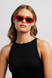 A model wearing the Siren Cats Eye Sunglasses in colour Red (Red), from the front, showing the whole outfit