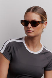 A model wearing the Wall Of Sound Sunglasses in colour Turtle, from the front, cropped image
