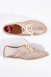 A model wearing size 38 of the Derby Punch Metallic Flat in colour Rosegold (Metallics), from the front, showing the whole outfit
