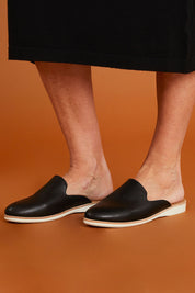 A model wearing size 37 of the Tumble Leather Derby Mule in colour Black (Black), from the front, showing the whole outfit