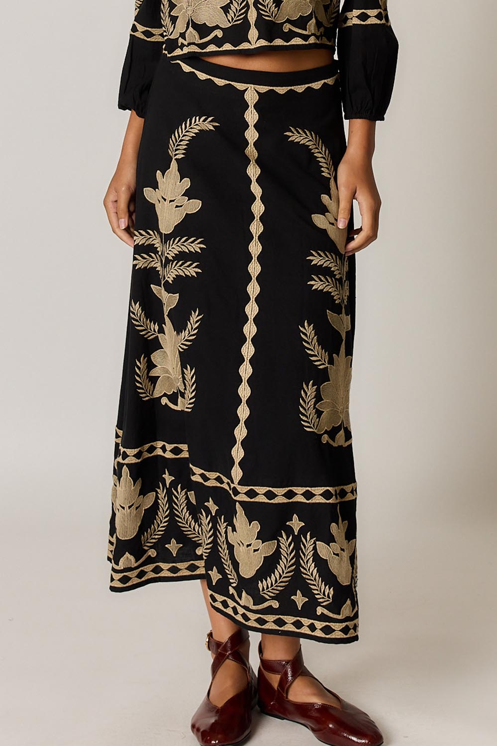 Model Genericm wearing size sample of the Arnun Skirt – Black in colour Black, in a cropped view