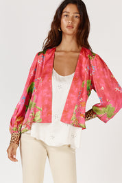 A model wearing the Mataram Bolero in colour Coral (Pink), from the front, cropped image