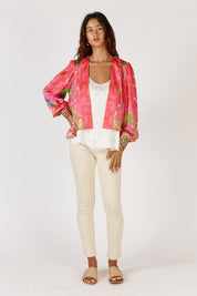 A model wearing the Mataram Bolero in colour Coral (Pink), from the front, showing the whole outfit