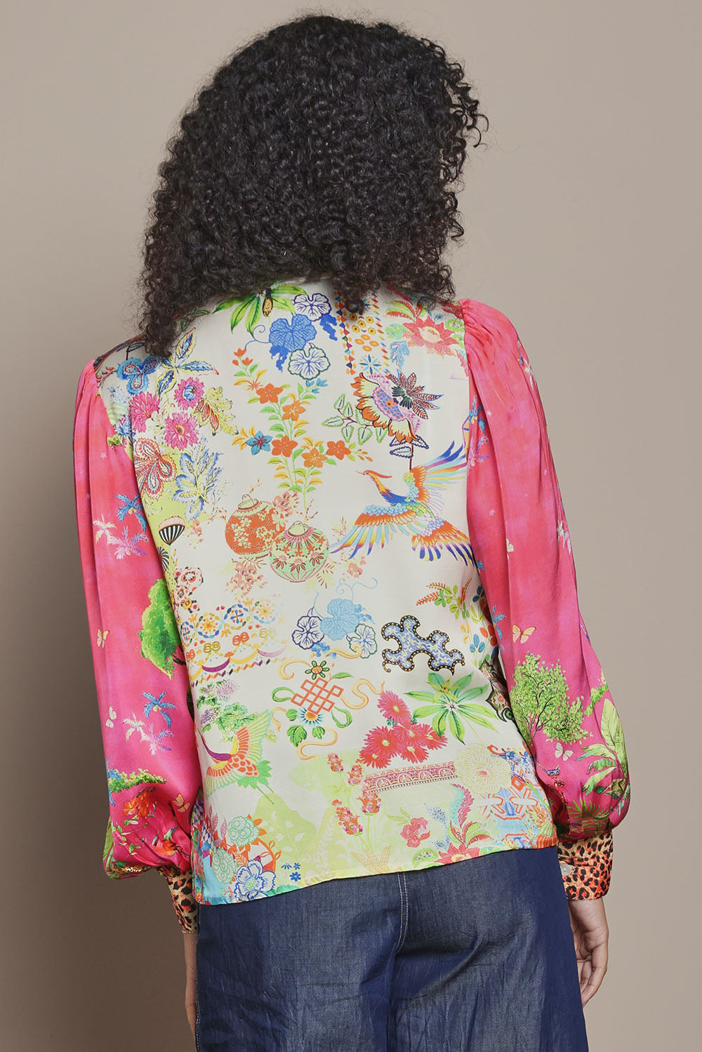 Model Ziara wearing size S of the Mataram Bolero in colour Coral (Pink), from the back