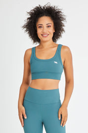 Model Olivia wearing size 10 of the Scoop It Up Sports Bra in colour Sage (Green), from the front, cropped image